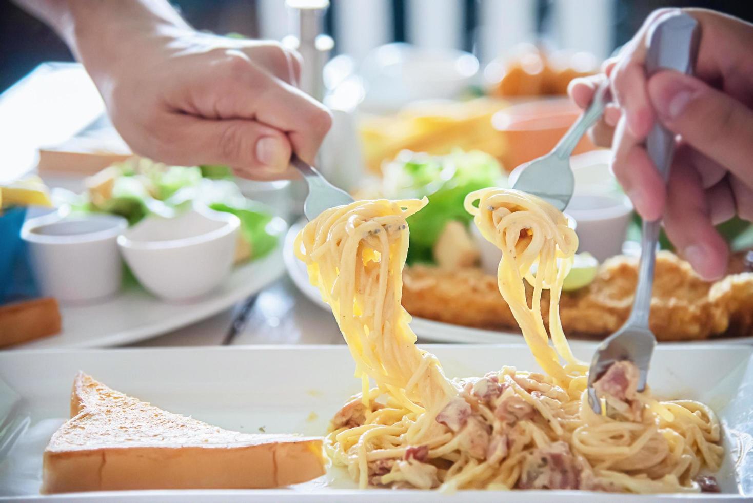 le persone si divertono a mangiare gli spaghetti insieme in un grande pasto - tempo felice per la famiglia con il concetto di cibo foto