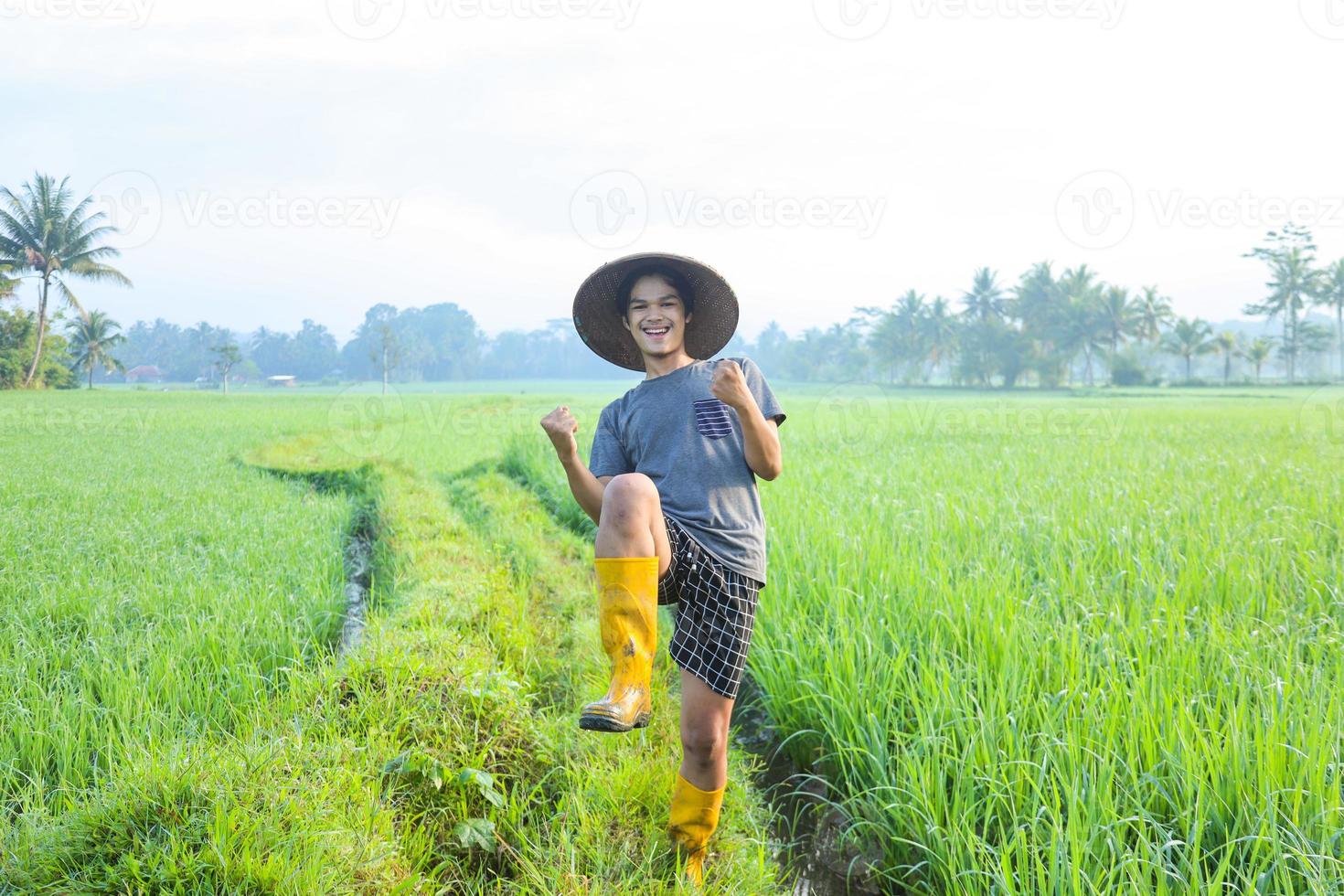 attraente giovane agricoltore asiatico allegro che si rallegra di avere successo nella coltivazione di risone nel campo di riso. concetto di agricoltura moderna. foto