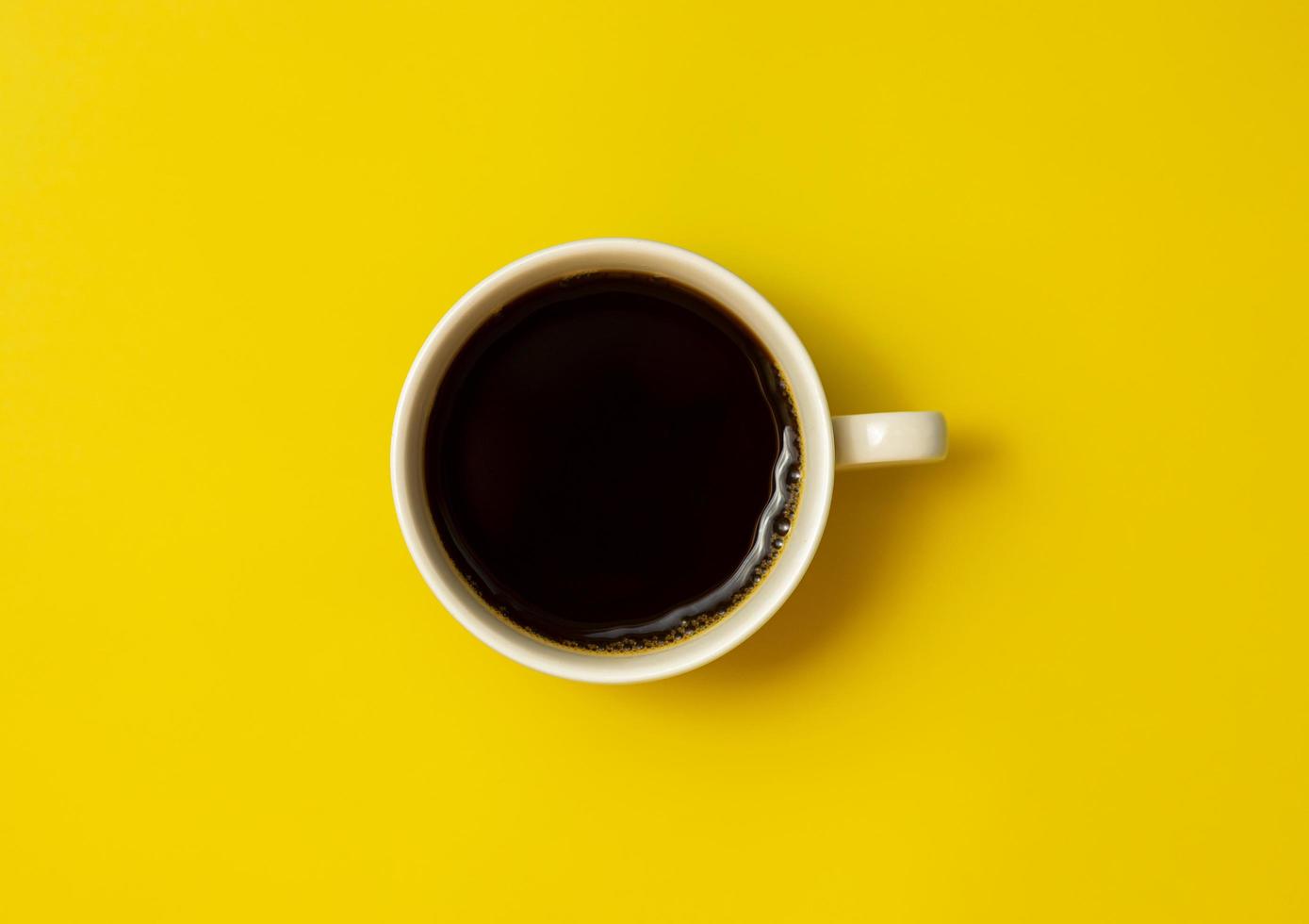vista dall'alto della tazza di caffè nero su sfondo giallo foto