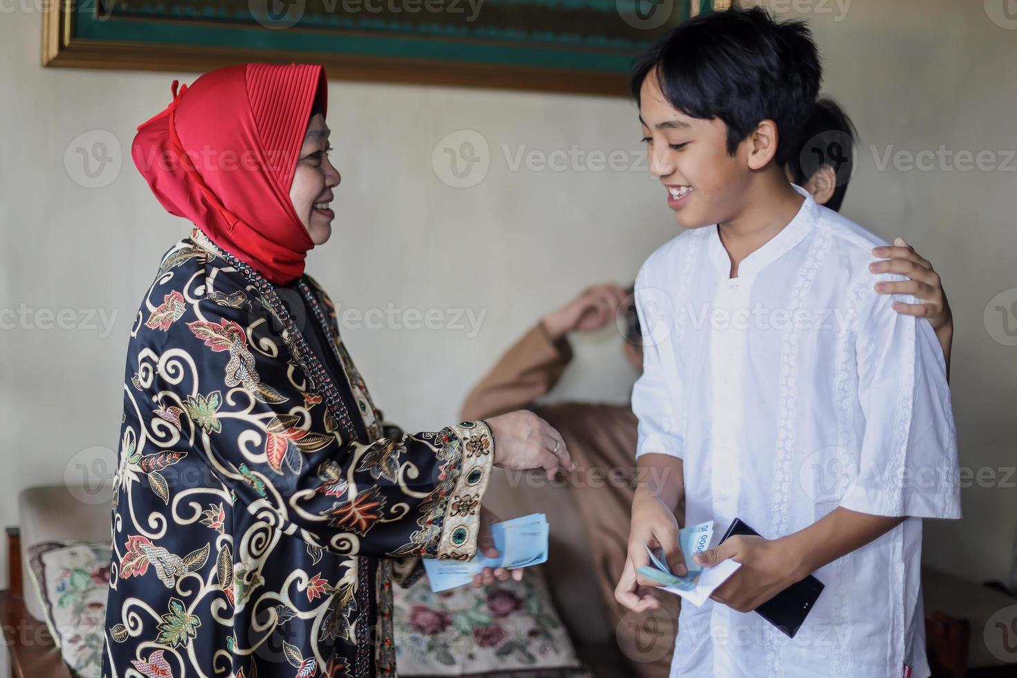 tradizione del popolo indonesiano durante la celebrazione di eid mubarak della distribuzione di denaro o chiamata thr. la nonna regala soldi al nipote di famiglia durante idul fitri. foto