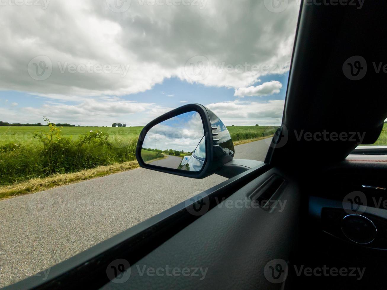 guardare nello specchietto laterale di un'auto sportiva nera durante la guida. foto