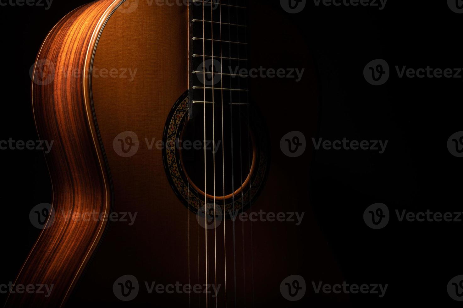 chitarra classica da vicino, drammaticamente illuminata su uno sfondo nero con spazio per la copia foto