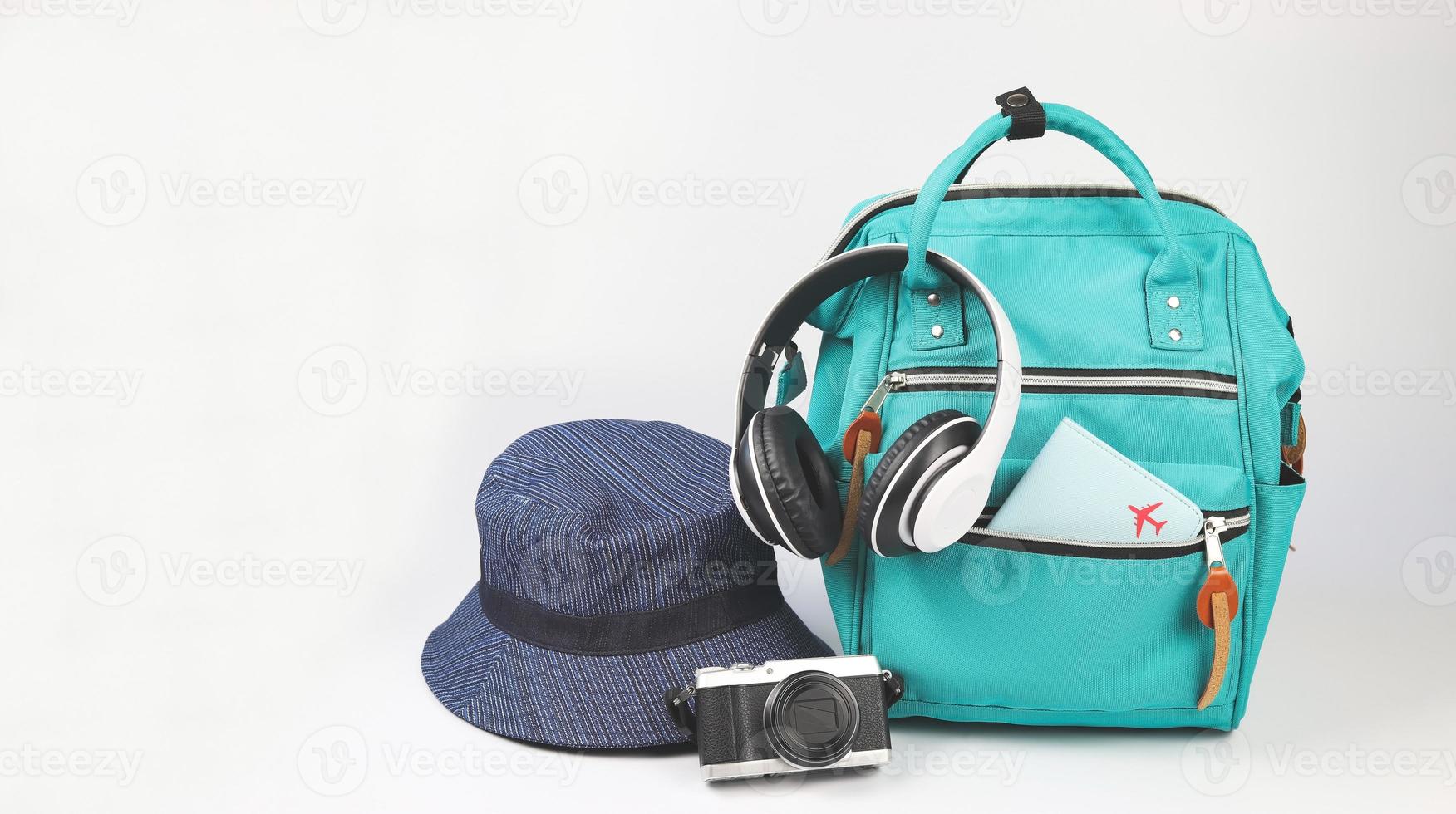 zaino verde con copertina del passaporto, cuffie, fotocamera e cappello a secchiello su sfondo bianco con spazio per la copia.. concetto di accessori da viaggio. foto