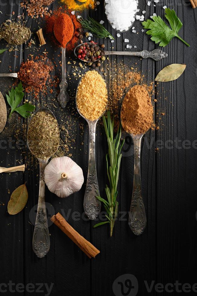 varie erbe e spezie colorate per cucinare su fondo rustico di legno scuro foto