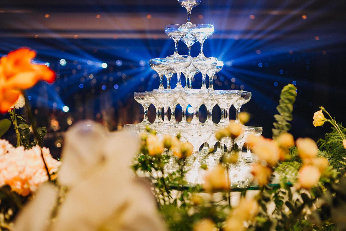 composizione floreale per il matrimonio estivo, fatta di rose e rami verdi su un tavolo da pranzo nel ristorante. , bicchieri e piatti nel ristorante all'aperto in una giornata ventosa con effetto grana della pellicola foto