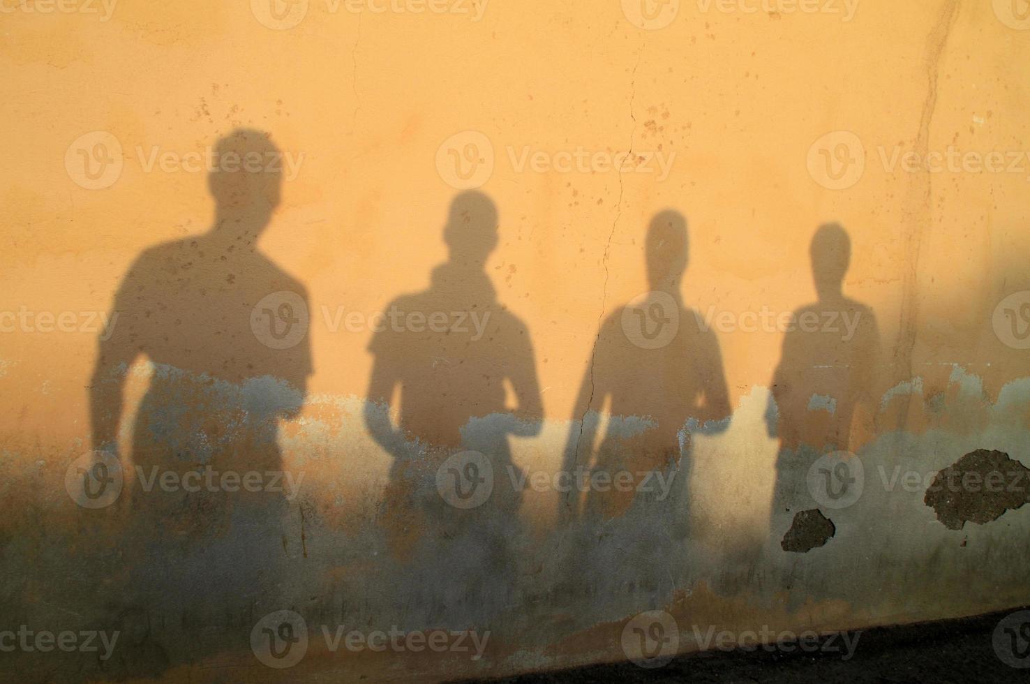 ombra di quattro amici contro un muro durante il tramonto foto