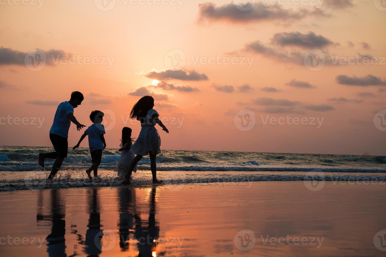 silhouette famiglia camminare e giocare al tramonto sulla spiaggia con i bambini concetto di vacanza felice foto