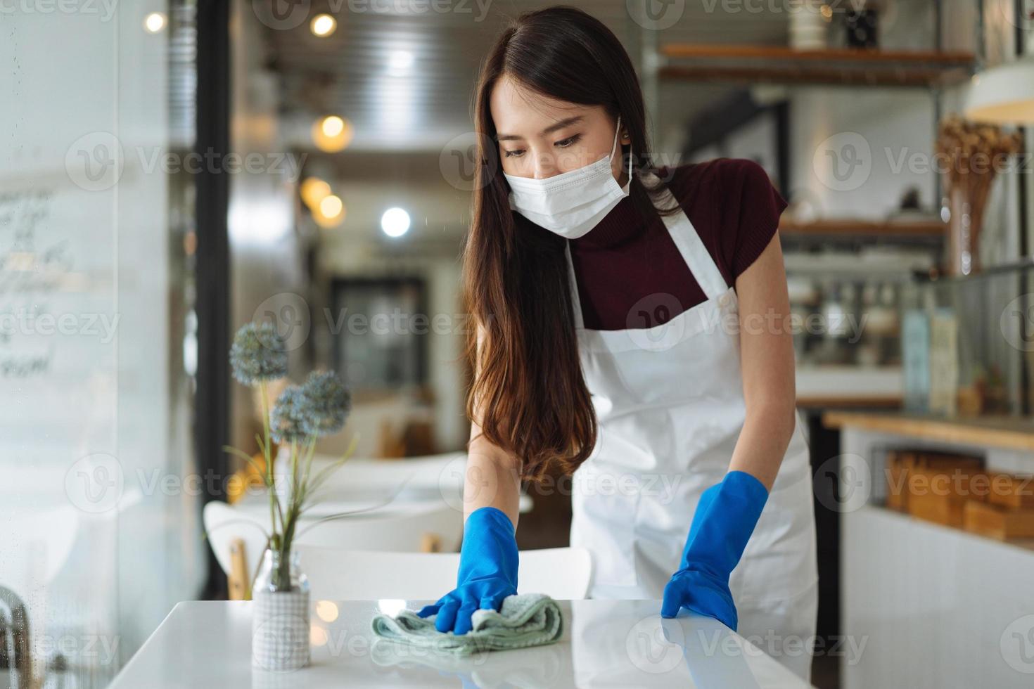 cameriera asiatica con maschera protettiva per il viso e visiera che serve caffè e pane in caffetteria. foto