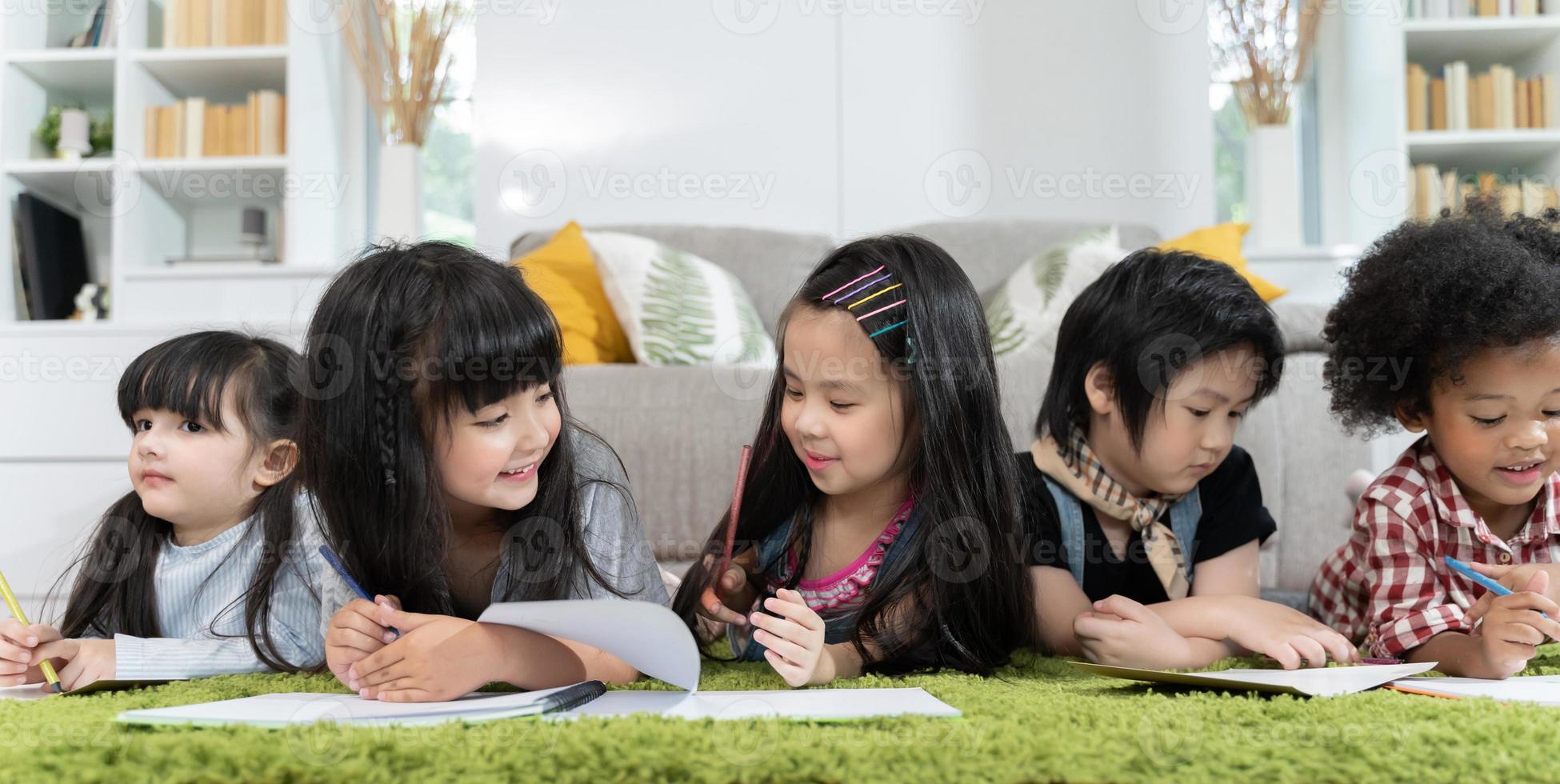 gruppo di bambini in età prescolare che disegnano carta con matite colorate. foto