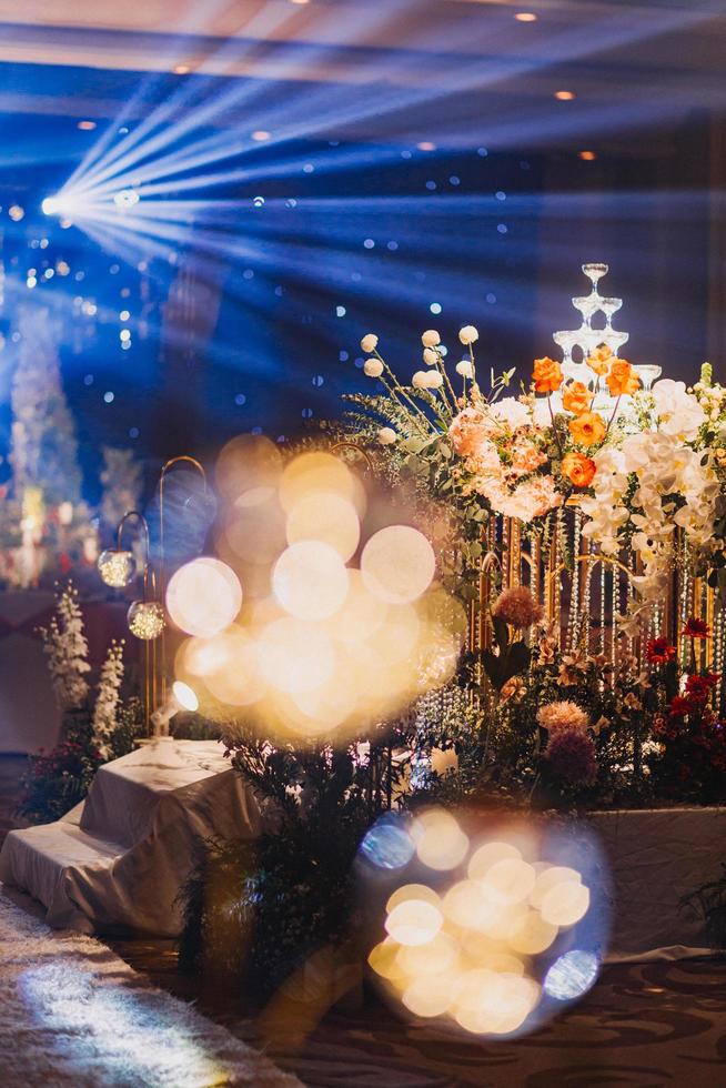 composizione floreale per il matrimonio estivo, fatta di rose e rami verdi su un tavolo da pranzo nel ristorante. , bicchieri e piatti nel ristorante all'aperto in una giornata ventosa con effetto grana della pellicola foto