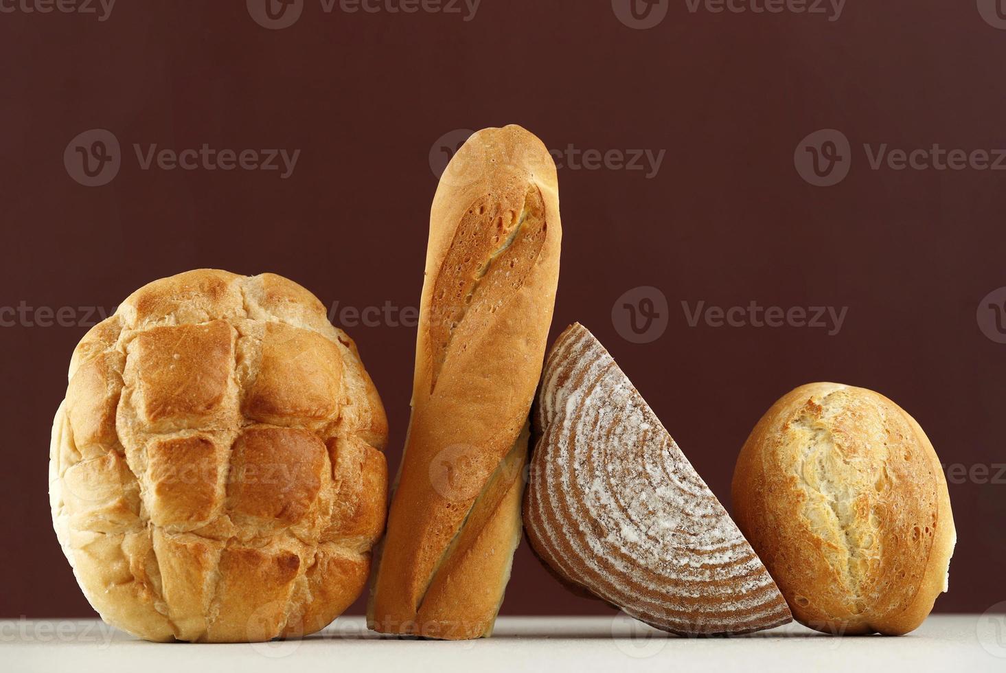 vari tipi di pane rustico, pasta madre, baguette, boule isolati su tavola marrone. foto