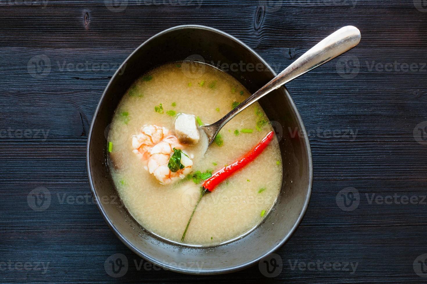 vista dall'alto della ciotola con zuppa di tom kha thale su oscurità foto