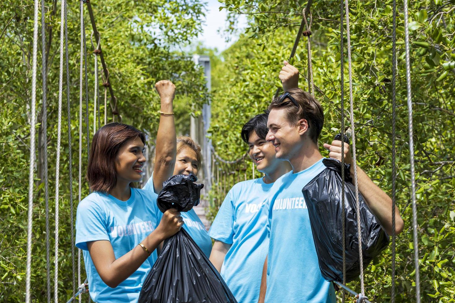 il team di giovani e diversi gruppi di volontari si divertono con il lavoro sociale di beneficenza all'aperto per ripulire il progetto di spazzatura nella foresta di mangrovie foto