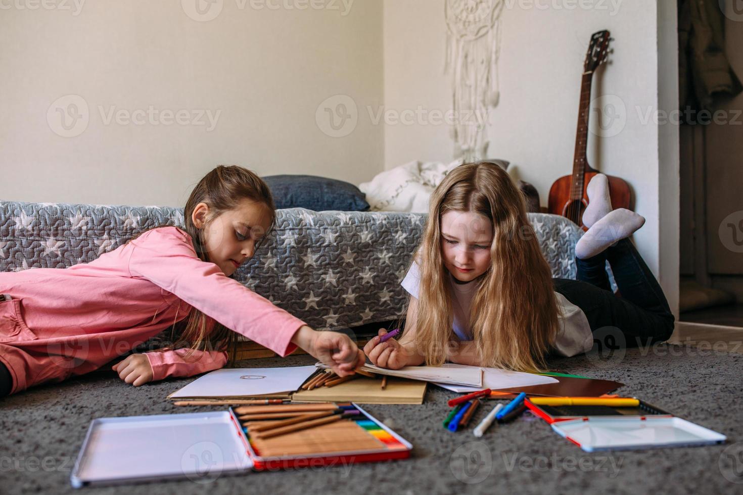 due amiche giocano in casa, disegnano con matite e pennarelli e si divertono foto