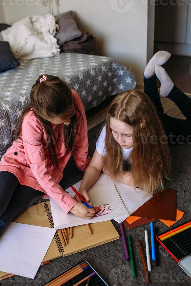 due amiche giocano in casa, disegnano con matite e pennarelli e si divertono foto