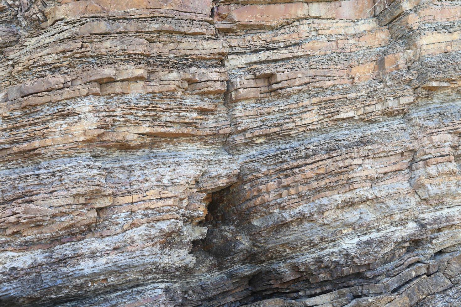 roccia stratificata su un'alta riva del mare ripida foto