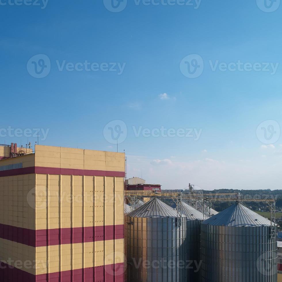 silo agricolo. stoccaggio ed essiccazione di cereali, grano, mais, soia, contro il cielo blu con nuvole. foto