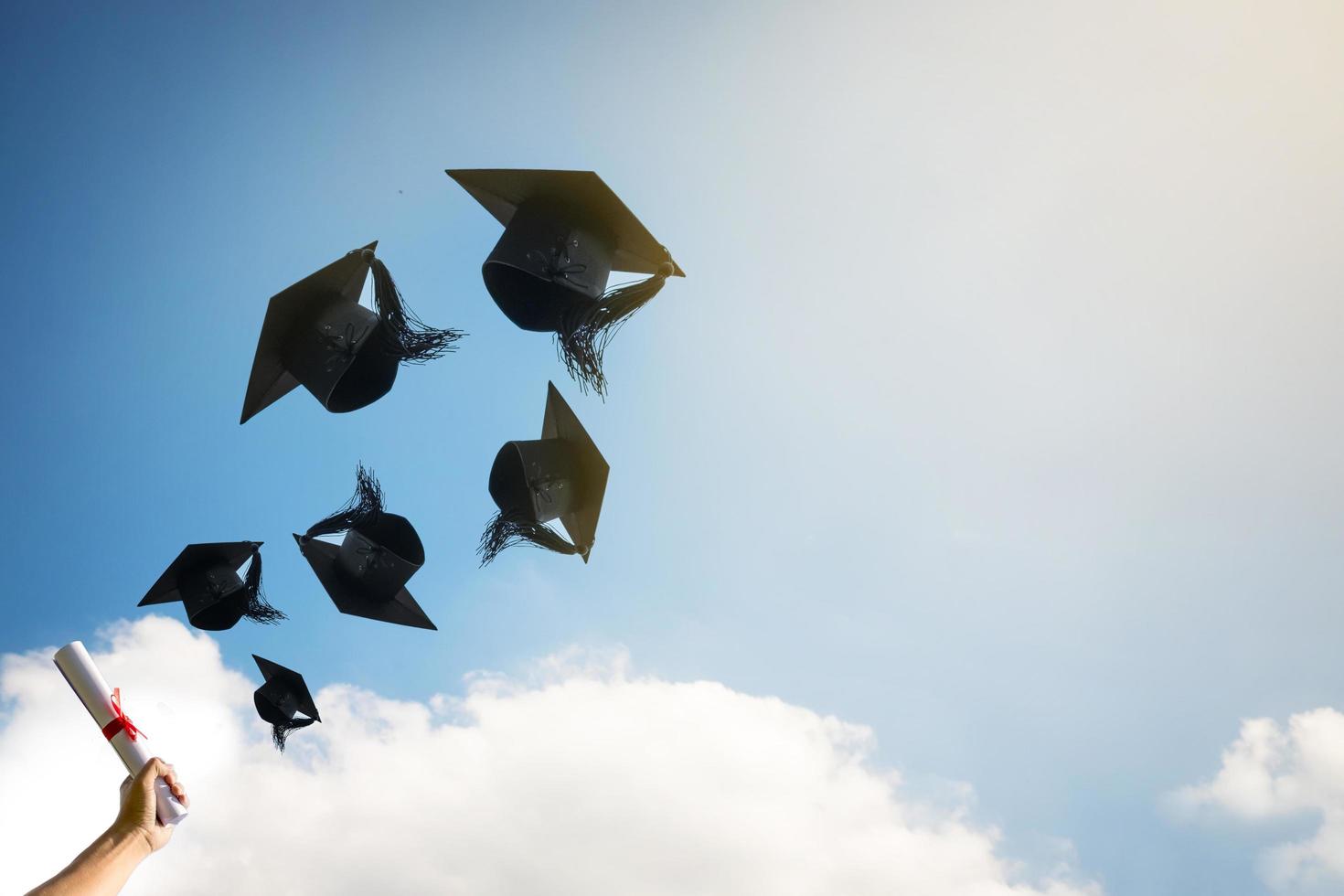 mani di laureati che lanciano cappelli di laurea. foto