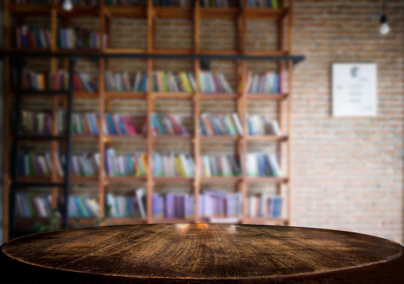 messa a fuoco selezionata tavolo in legno marrone vuoto e libreria o libreria sfocano lo sfondo con l'immagine bokeh. per il tuo fotomontaggio o la visualizzazione del prodotto. foto