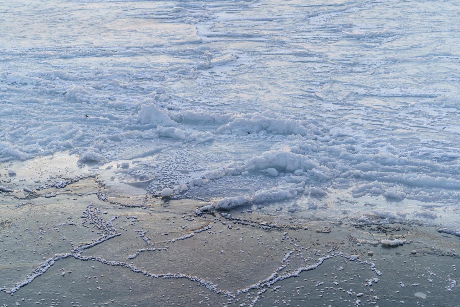 superficie dell'acqua ghiacciata con crepe e banchi di ghiaccio foto
