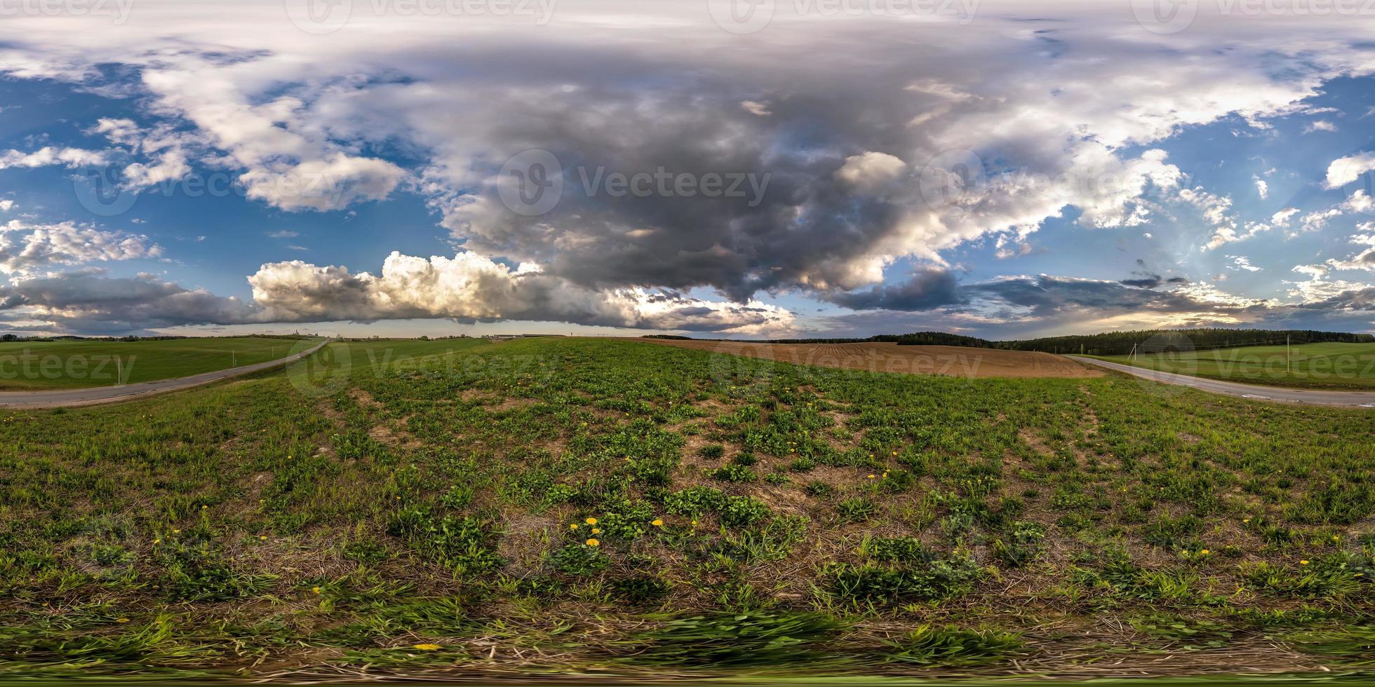 panorama hdri sferico completo senza soluzione di continuità vista a 360 gradi tra i campi in serata primaverile con fantastiche nuvole prima della tempesta in proiezione equirettangolare, pronto per contenuti di realtà virtuale vr ar foto