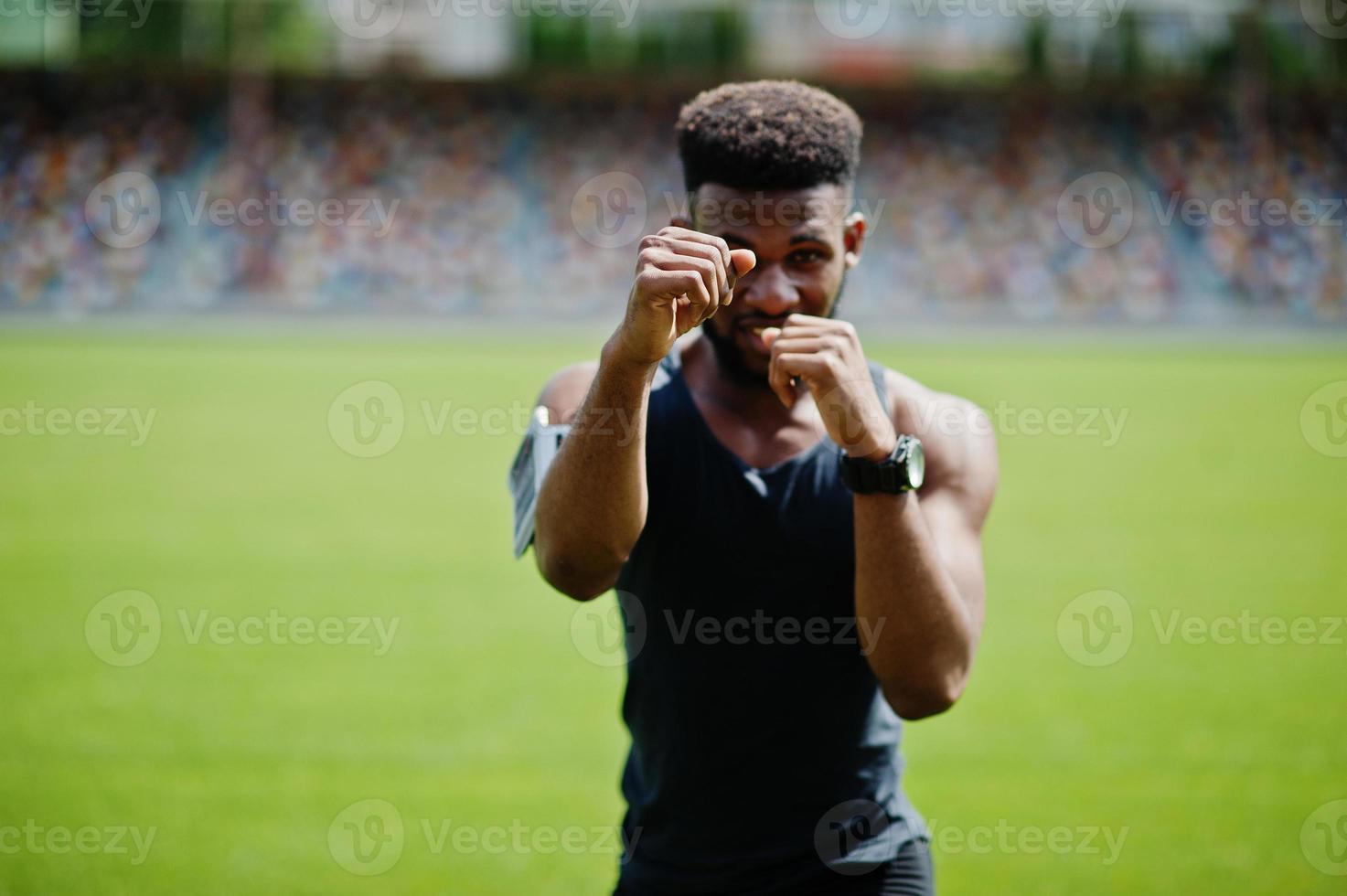 atleta maschio afroamericano pugile uomo in abbigliamento sportivo che fa stretching allo stadio. foto