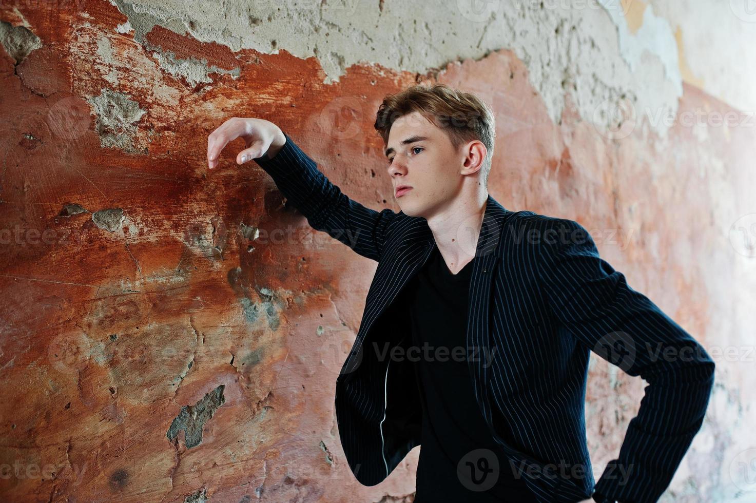 giovane ragazzo macho alla moda in giacca nera posato all'aperto di strada. fantastico uomo modello. foto