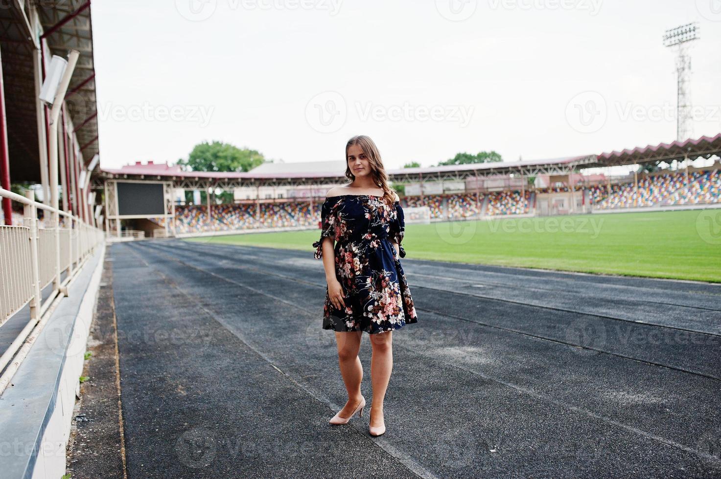 ritratto di una favolosa ragazza in abito e tacchi alti in pista allo stadio. foto