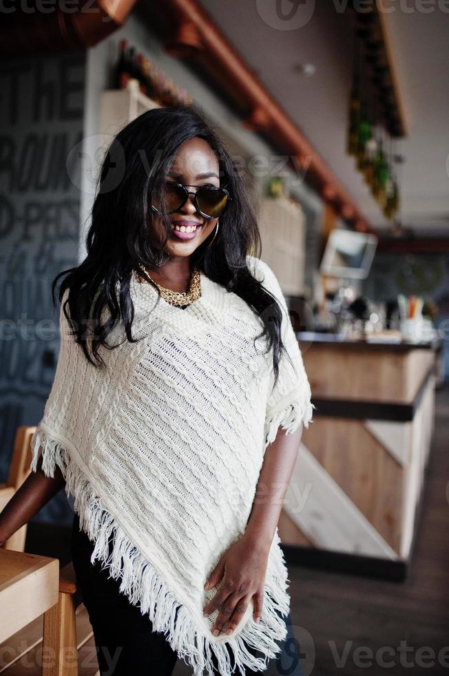 elegante ragazza afroamericana in occhiali da sole poste al caffè moderno. foto