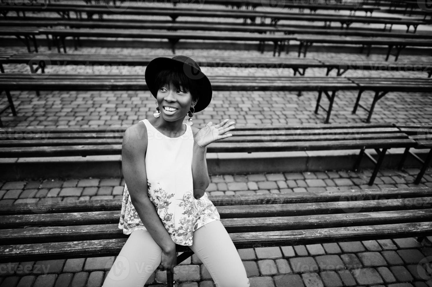 incredibile donna modello afroamericano in pantaloni verdi e cappello nero poste in panchina. foto