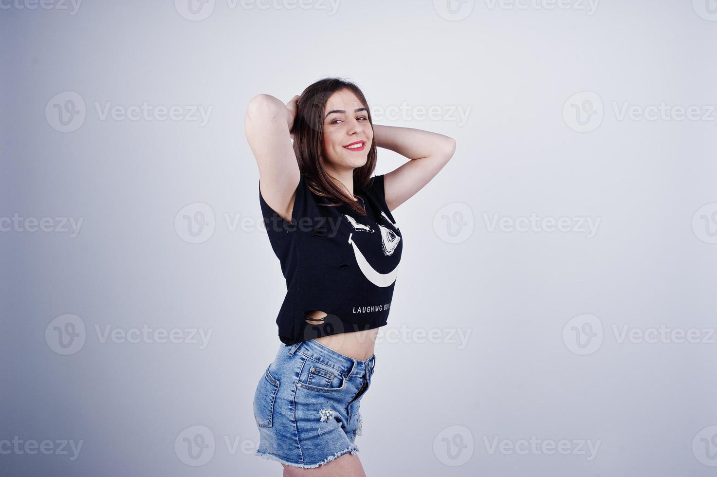 ritratto di una ragazza attraente in maglietta nera che dice lol e pantaloncini di jeans in posa in studio. foto