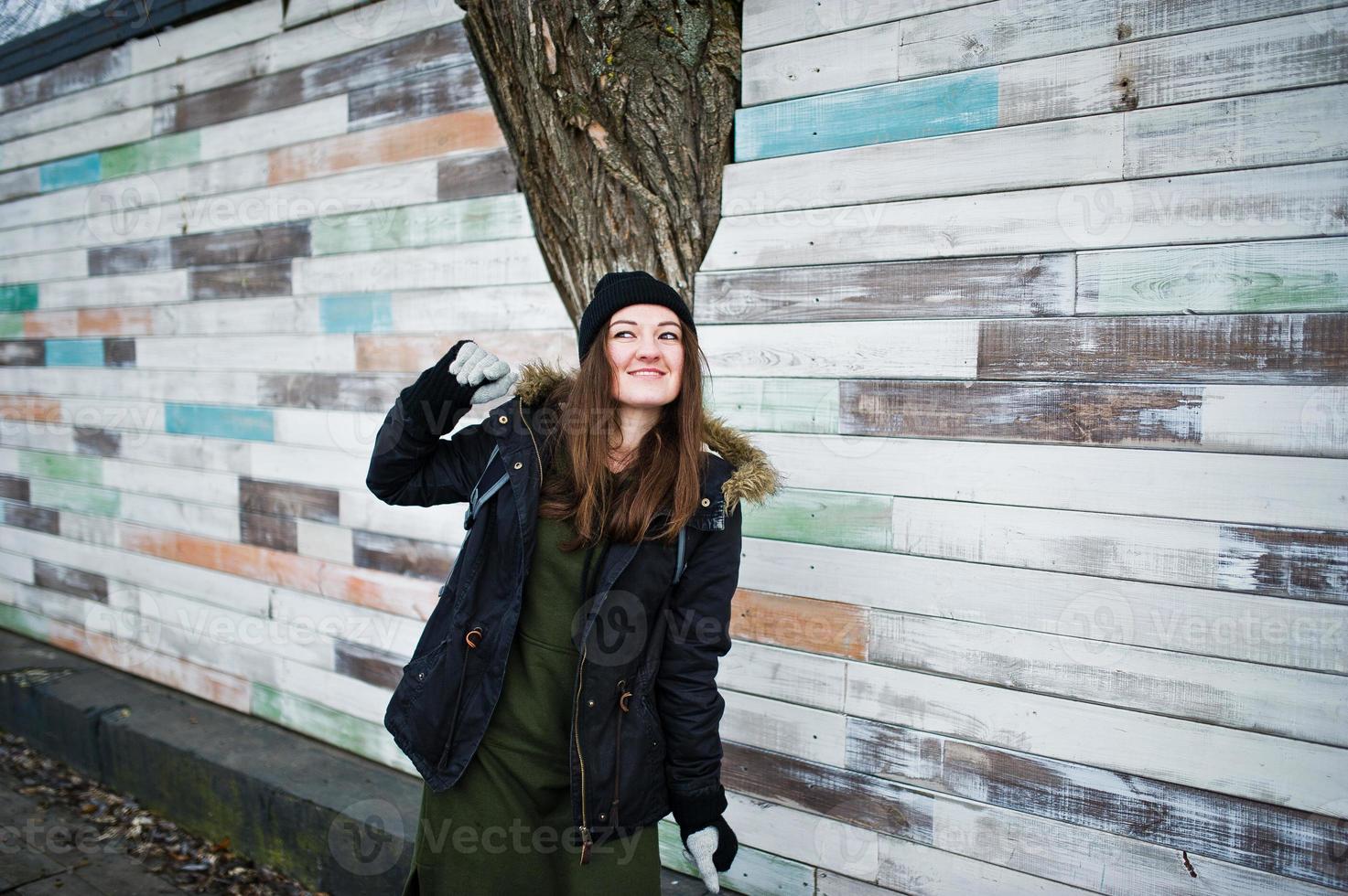 la ragazza indossa un copricapo nero contro la parete di legno. foto