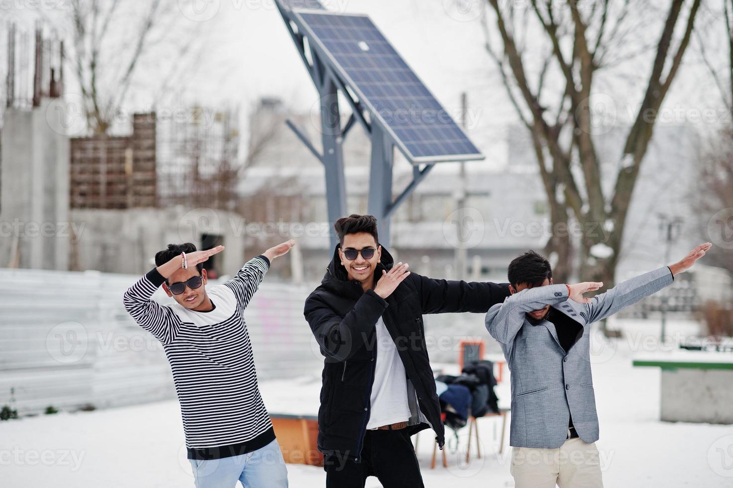 un gruppo di tre giovani indiani casuali in occhiali da sole poste in una giornata invernale, mostra dab. foto