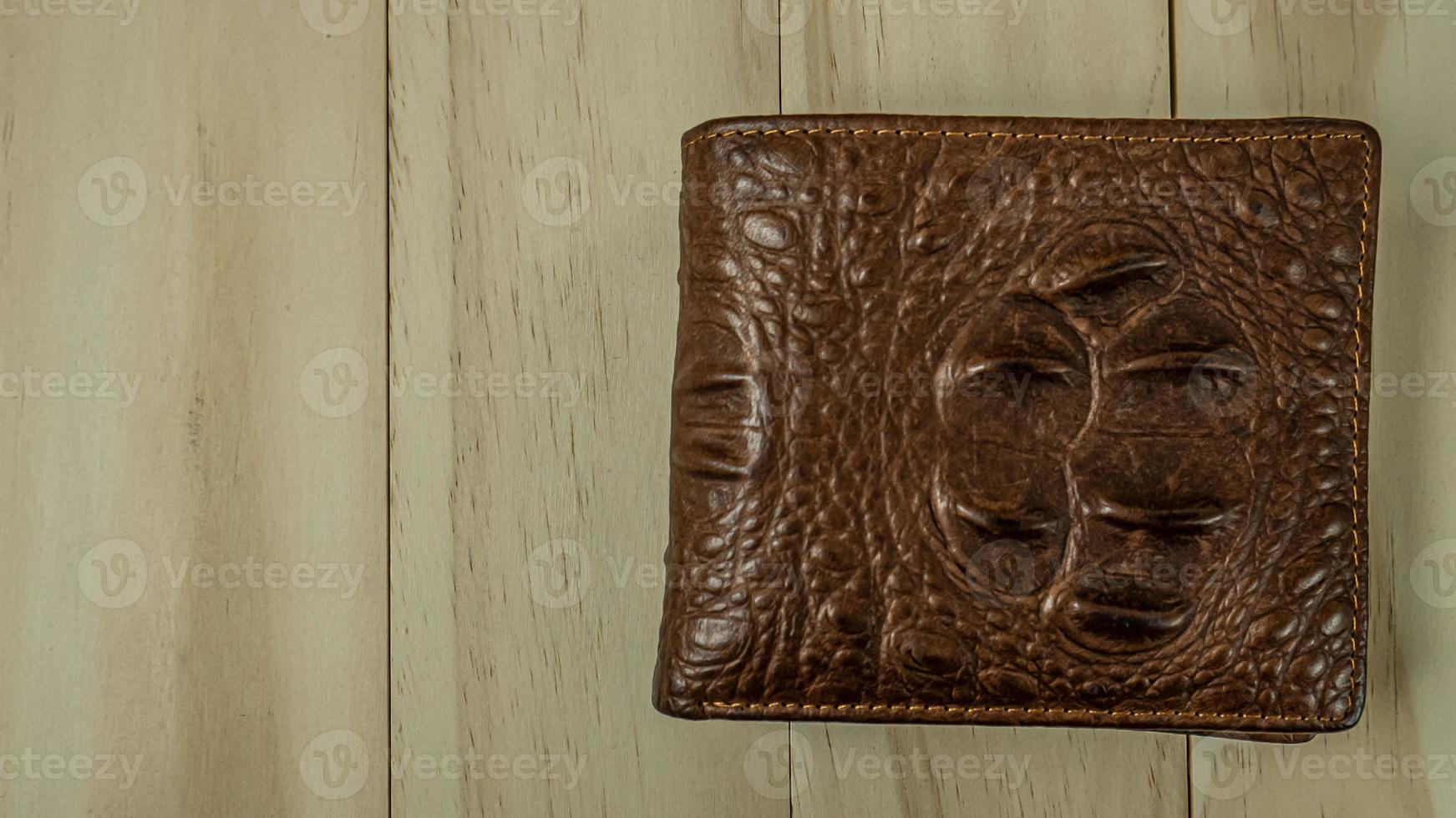 il portafoglio in pelle di coccodrillo sul tavolo di legno. foto