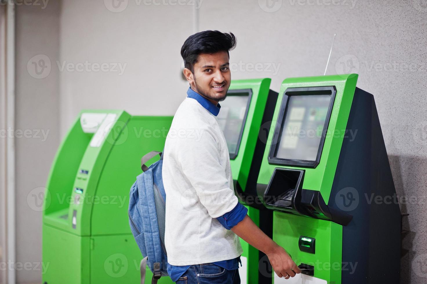 il giovane uomo asiatico ha messo la sua carta di credito per rimuovere i contanti da un bancomat verde. foto