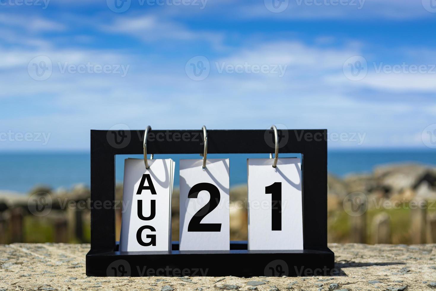 21 agosto testo della data del calendario su telaio in legno con sfondo sfocato dell'oceano. foto