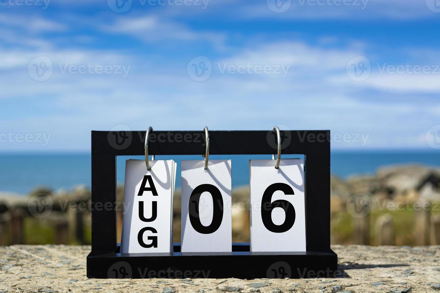 ago 06 testo della data del calendario su telaio in legno con sfondo sfocato dell'oceano. foto