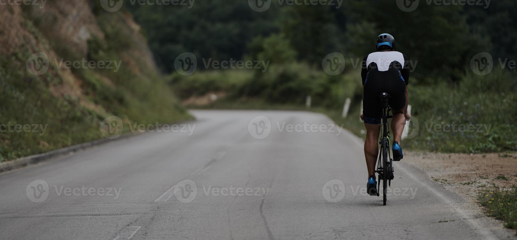 atleta di triathlon in sella a una bicicletta vestita di nero foto