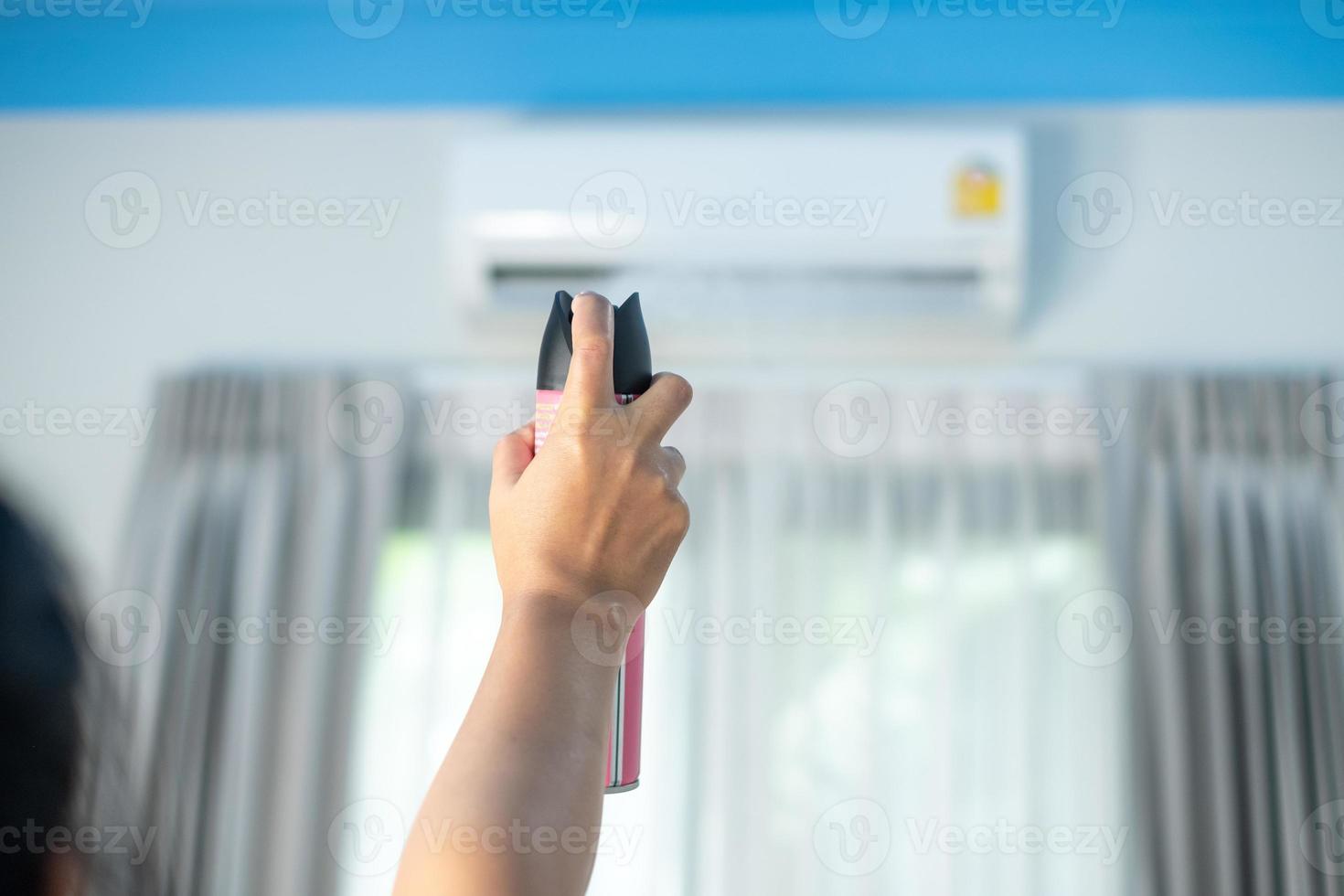 mano della donna che tiene e spruzza deodorante spray al condizionatore d'aria in camera da letto odore di muffa, muffa, stagione delle piogge, igiene nel concetto di vita quotidiana foto