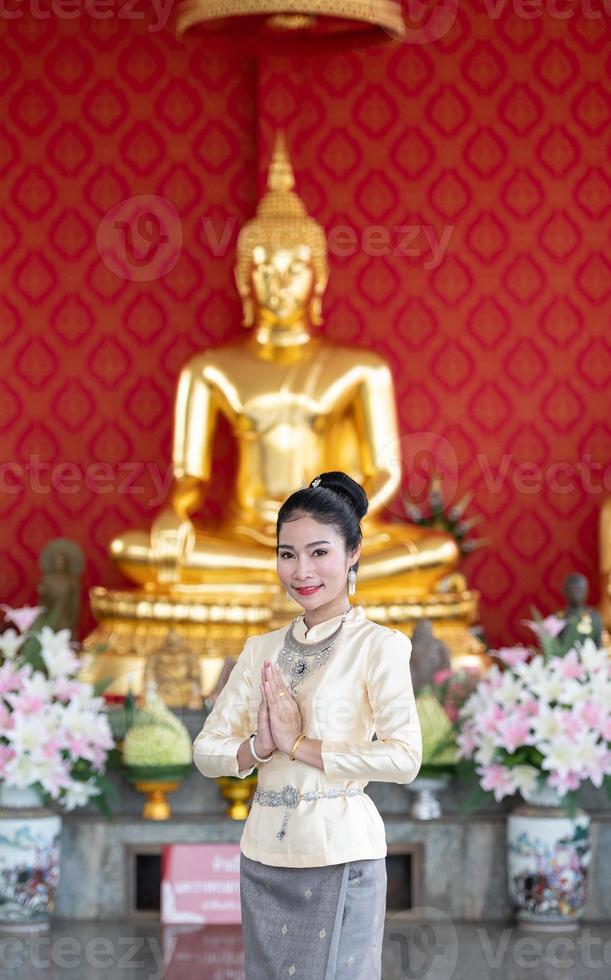 una donna che indossa abiti tailandesi in onore del simbolo sawasdee. foto