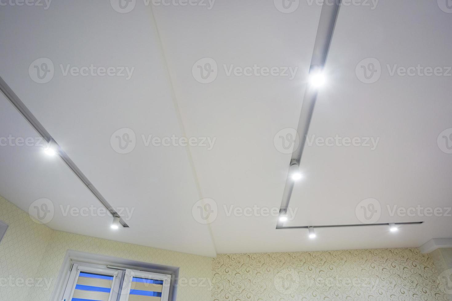 lampade alogene su controsoffitto e costruzione di muri a secco in stanze vuote in appartamenti o case. soffitto teso bianco e di forma complessa. foto