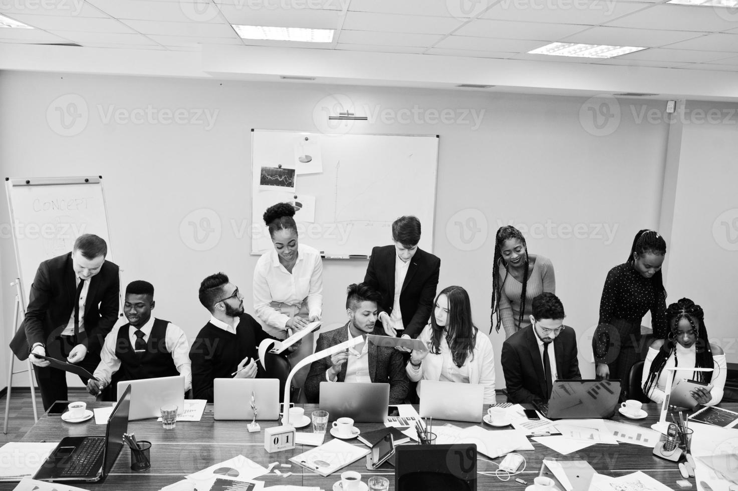 giovani creativi multirazziali in un ufficio moderno. gruppo di giovani uomini d'affari stanno lavorando insieme con laptop, tablet. team di freelance di successo nel coworking. foto