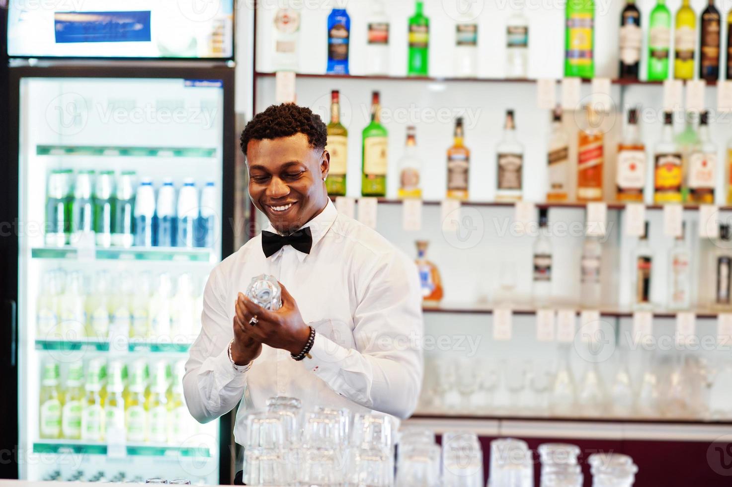 il barista afroamericano indossa gli occhiali per la pulizia del farfallino al bar. foto