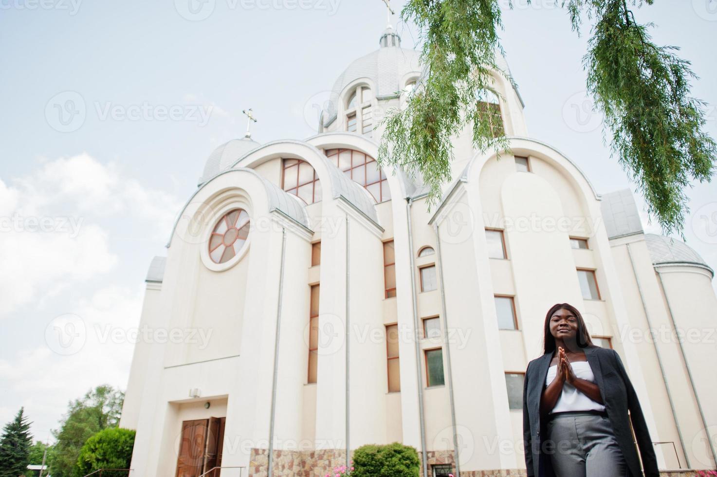 donna afroamericana all'aperto contro la chiesa e prega Dio. concetto di fede, spiritualità e religione. foto