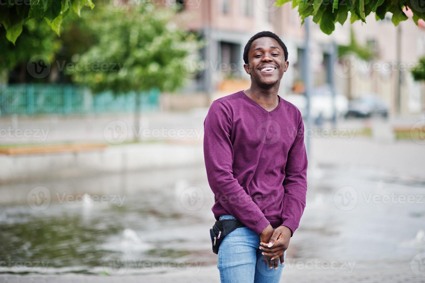 giovane uomo afroamericano in maglione viola posato contro il vicolo della fontana. foto