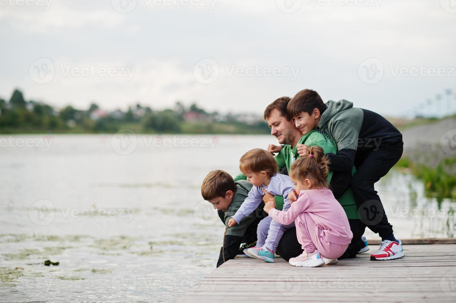 amore del padre. papà con quattro figli all'aperto sul molo. sport la famiglia numerosa trascorre il tempo libero all'aria aperta. foto