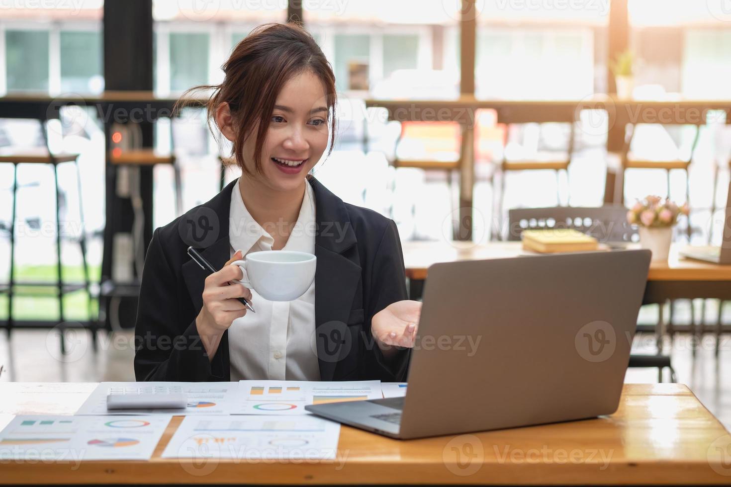 marketing, finanza, contabilità, pianificazione, donna d'affari che tiene una tazza di caffè analisi dei profitti della riunione online con statistiche del grafico utilizzare un laptop e una calcolatrice per calcolare il saldo aziendale. foto