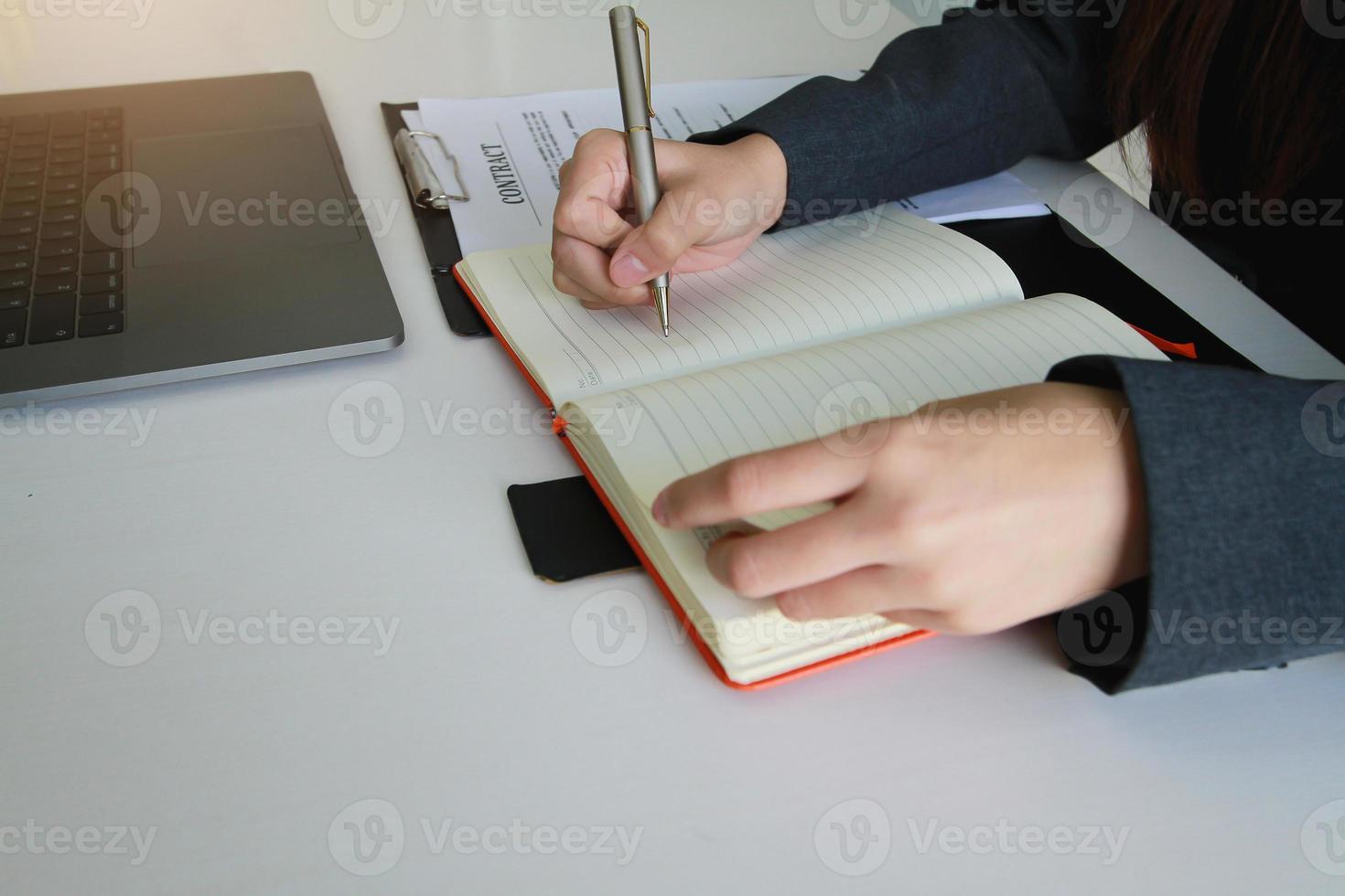 donna che tiene sta scrivendo su un taccuino con una penna in ufficio. foto