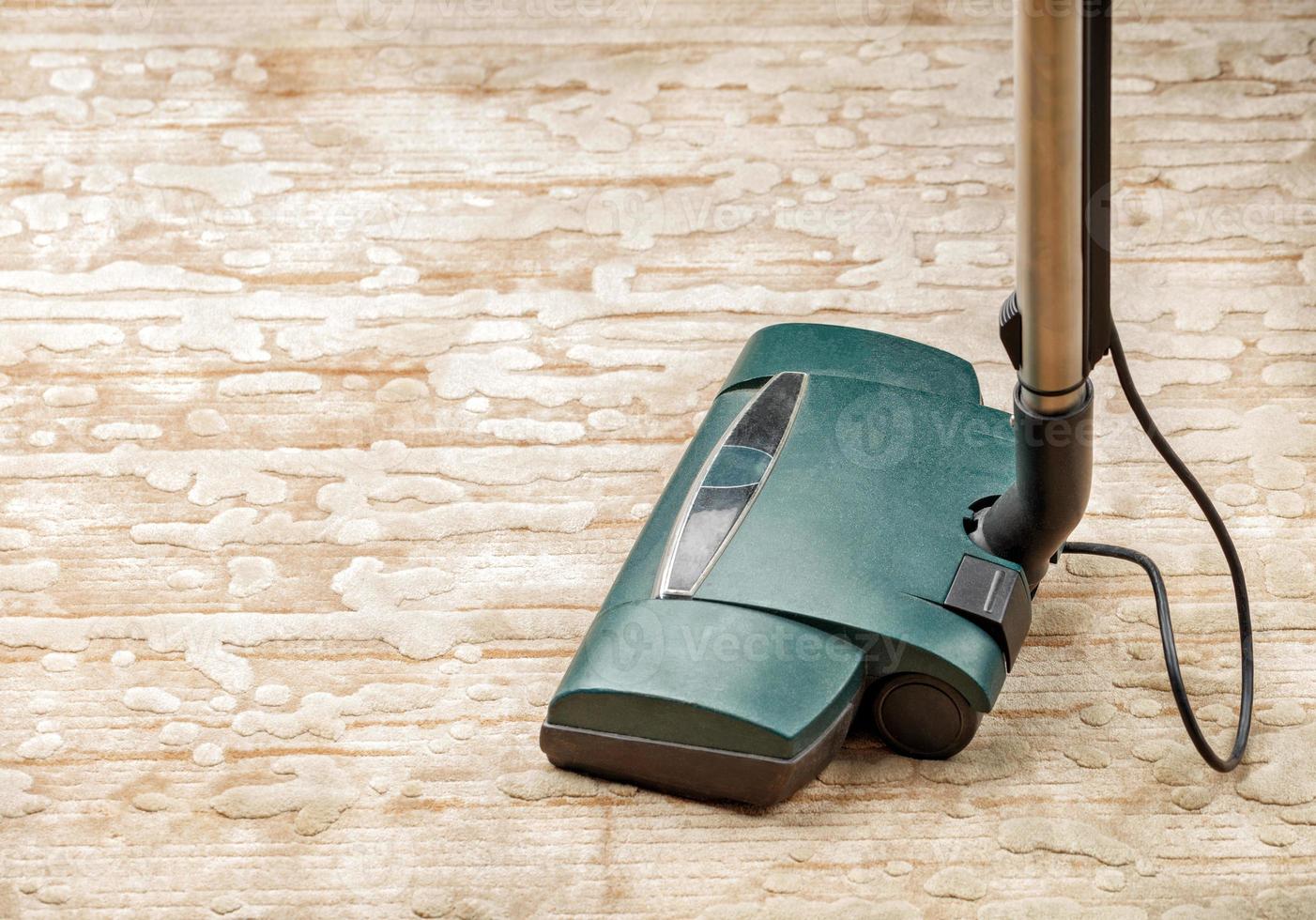 la spazzola di un aspirapolvere elettrico sullo sfondo di un pavimento in moquette beige. foto