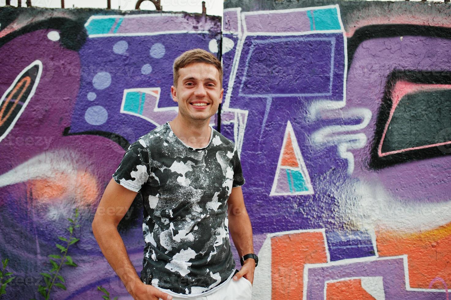 ritratto di stile di vita di bell'uomo in posa sulla strada della città con muro di graffiti. foto